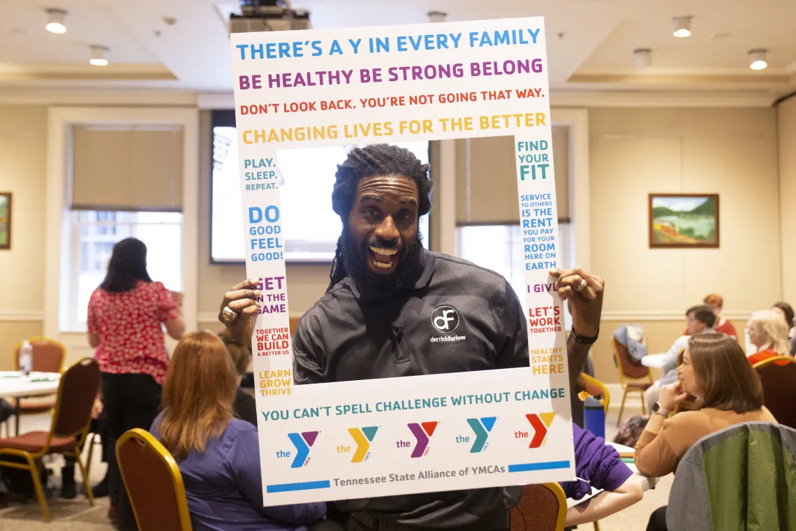 Man smiles within YMCA photo frame prop